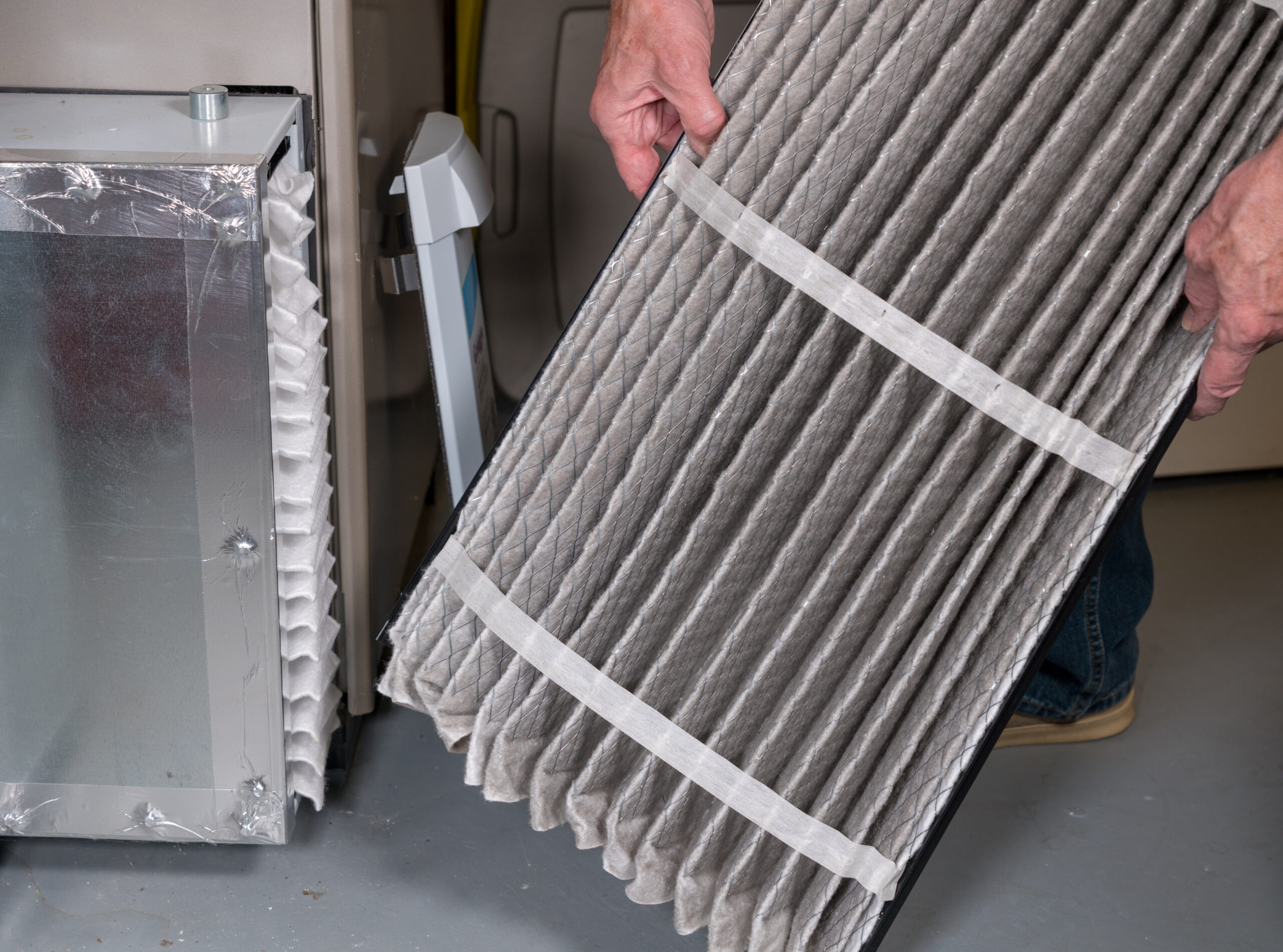 Senior man changing a dirty air filter in a HVAC Furnace