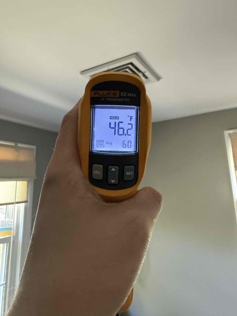 Technician measuring about 46 degree supply air at a ceiling register in Sherborn, MA